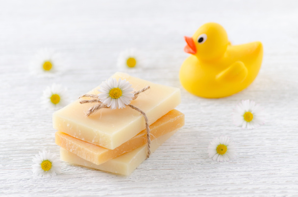 jabón natural hecho a mano con flores de manzanilla y un juguete de pato
 - Foto, imagen
