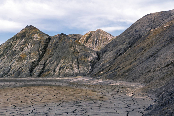 пейзаж - порожнина з сухим глиняним дном серед пустельних неживих пагорбів
 - Фото, зображення