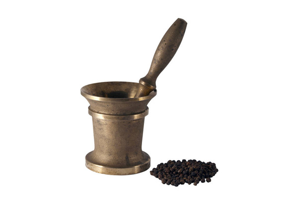 mortero de bronce patinado antiguo y un puñado de guisantes de pimienta negro aislados
 - Foto, imagen