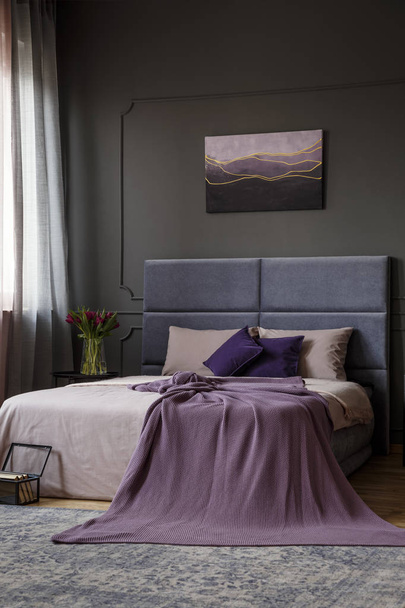 Pink blanket on bed with headboard against grey wall with poster in elegant bedroom interior - Fotó, kép