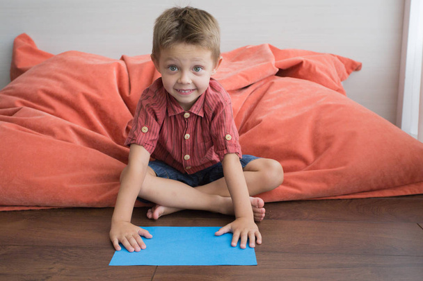 der Junge zu Hause sitzt auf dem Boden und macht handgeschöpftes Papier. - Foto, Bild