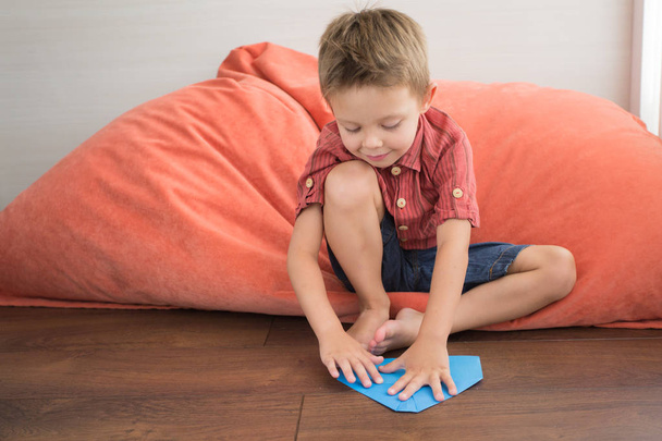 der Junge zu Hause sitzt auf dem Boden und macht handgeschöpftes Papier. - Foto, Bild