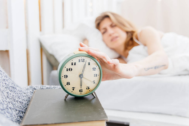 Young woman turns off the alarm clock in the morning - Φωτογραφία, εικόνα