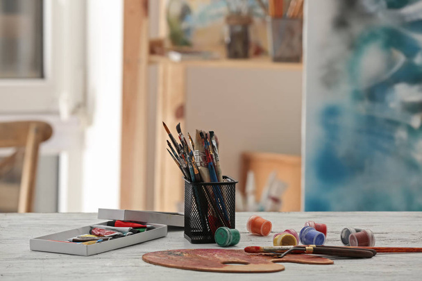 Soporte con pinceles y pinturas sobre mesa
 - Foto, Imagen