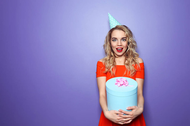 Portrait of beautiful young woman with birthday gift on color background - Photo, Image