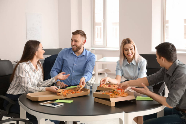 Jovens comendo pizza à mesa no escritório
 - Foto, Imagem