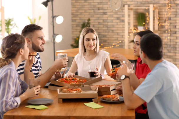 Les jeunes mangent de la pizza à table
 - Photo, image