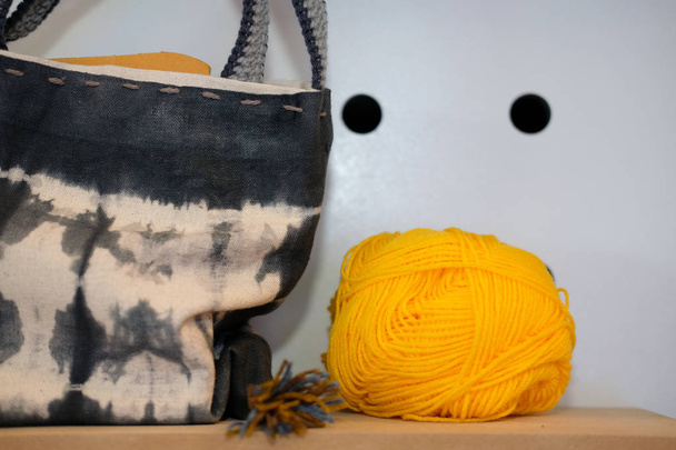ネクタイ染めファブリック手バッグ ・編み糸のボール。手作り手芸刺繍小物 - 写真・画像