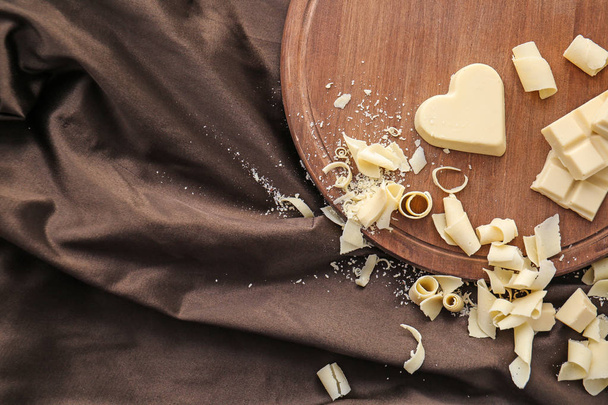 Wooden board with pieces of chocolate and curls on fabric - Photo, Image
