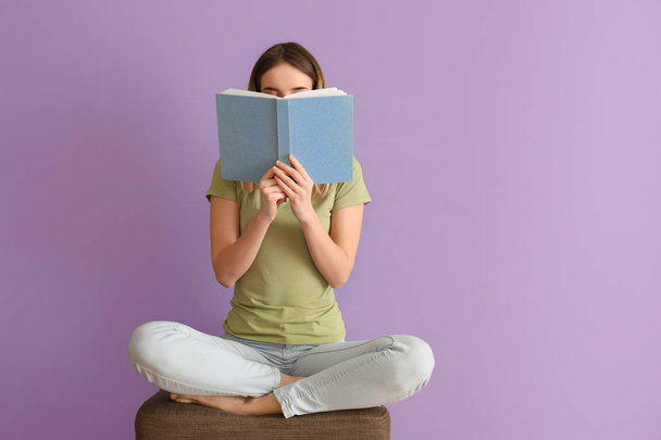Fiatal nő olvasó könyv színes fal közelében - Fotó, kép