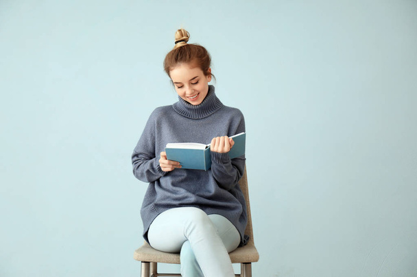 Fiatal nő olvasó könyv színes fal közelében - Fotó, kép