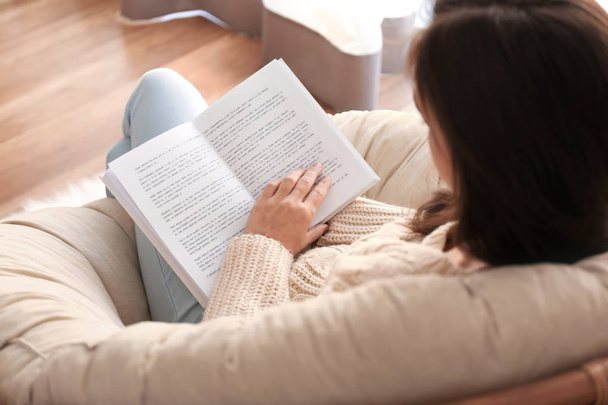 Giovane donna lettura libro sulla poltrona a casa
 - Foto, immagini