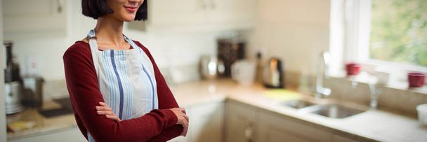 Waitress in spectacles standing with arms crossed against kitchen interior - Photo, image