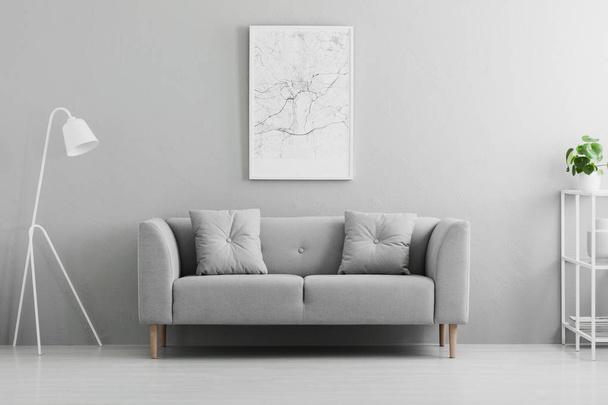 White lamp next to grey couch in minimal living room interior with poster and plant. Real photo - Foto, immagini