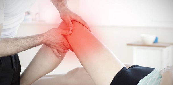 Handsome young physical therapist giving a leg massage against highlighted pain - Фото, изображение