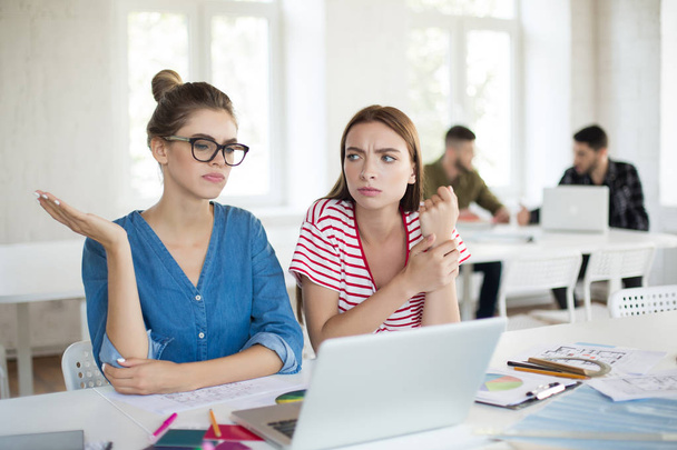 Młody zdenerwowany kobiet starannie pracy wraz z laptopa. Grupa ludzi, spędzać czas w nowoczesnym biurze - Zdjęcie, obraz