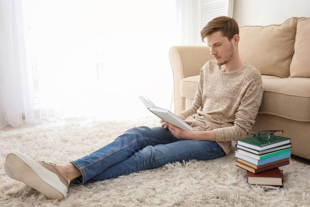 Young man reading books at home - Fotó, kép