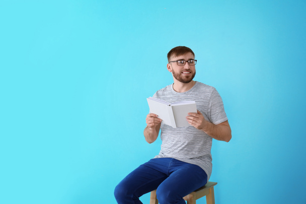 Young man with book on color background - Photo, Image