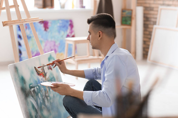 Male artist painting on canvas in workshop - Foto, Imagem