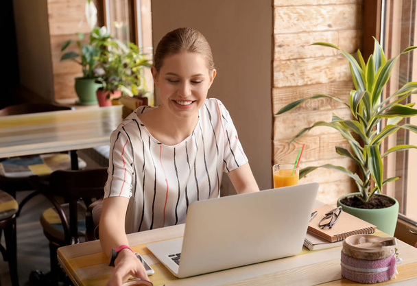 Joven freelancer con laptop trabajando en cafetería
 - Foto, imagen