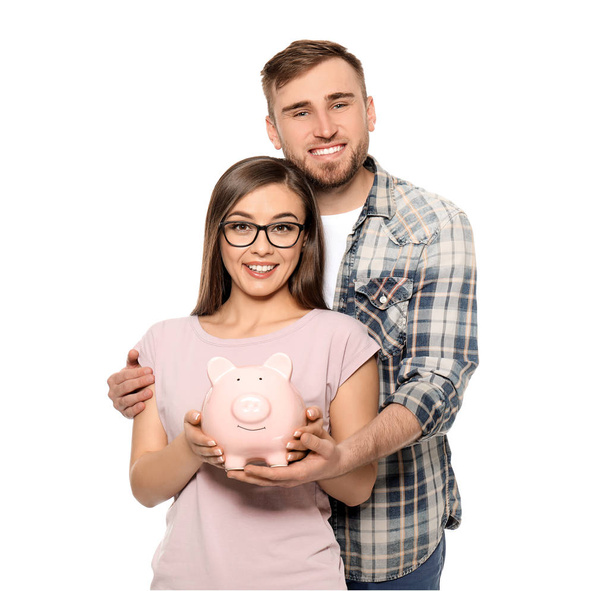 Happy couple holding piggy bank on white background. Money savings concept - Photo, image