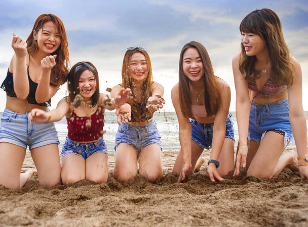 muotokuva onnellinen ja iloinen ryhmä aasialaisia korealaisia ja kiinalaisia nuoria naisia, tytöt leikkivät hiekalla yhdessä polvistuvat rannalla tyttöystäviä loma matka ja ystävyys käsite
 - Valokuva, kuva