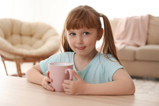 Linda niña con taza de bebida caliente de cacao en casa
 - Foto, imagen