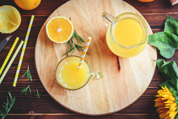 Glass of fresh pressed orange juice and oranges on wooden table. Autumn cozy rustic mood still life - Photo, image