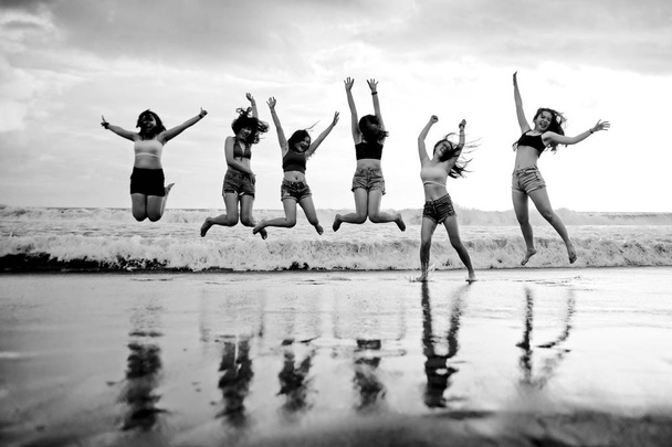 lifestyle beach portrait of young group of Asian Korean and Chinese women , happy and attractive girlfriends enjoying Summer holidays jumping on the air in the sea having fun together - Photo, Image