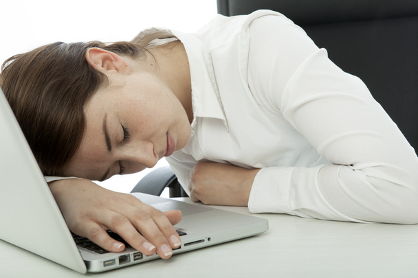 jonge brunette zakenvrouw in slaap vallen op haar computer - Foto, afbeelding