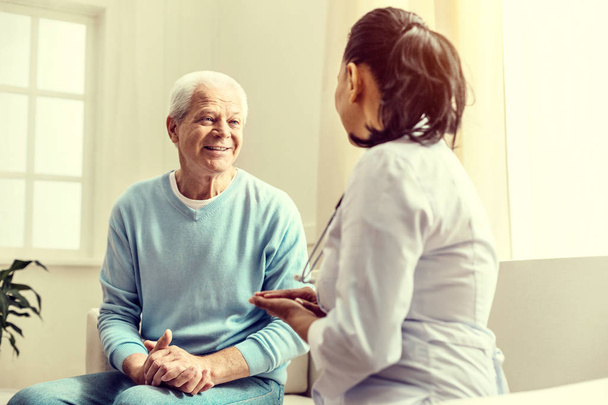 Cheerful elderly gentleman consulting with nurse - Фото, изображение