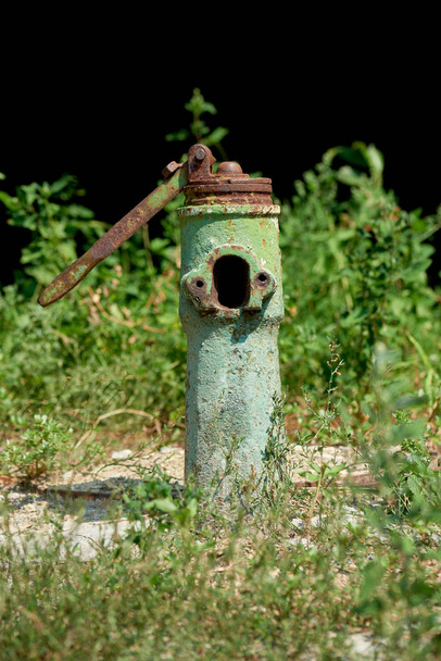 close up view of old grungy water fountain and green plants behind - Photo, Image