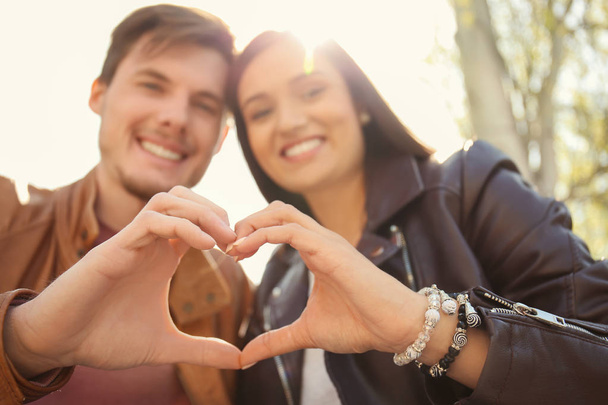 Lovely couple holding hands in shape of heart outdoors - Foto, Imagem