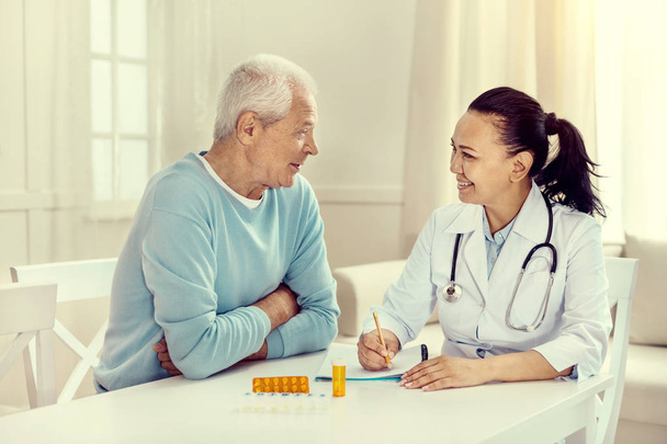 Positive minded elderly man and nurse discussing treatment - Foto, Imagen