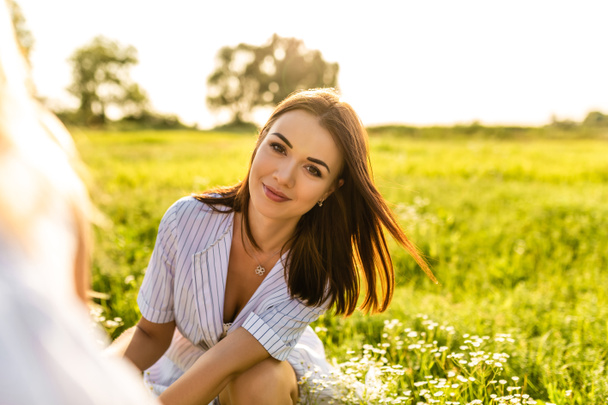 jeune femme heureuse regardant la caméra tout en étant assis sur le champ vert
 - Photo, image