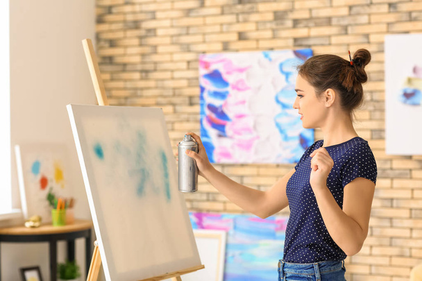 Artiste féminine avec peinture en aérosol travaillant en studio
 - Photo, image