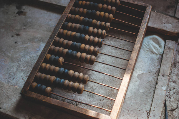Old wooden abacus laying on the dusty floor of the storage. Closeup - Photo, Image