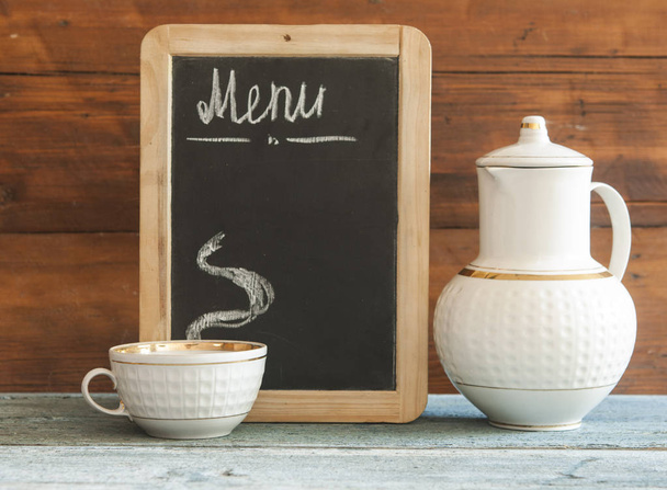 filiżanka biała i mała tablica na drewnianym blatem. W menu. Karta herbaty. Karta kawowa - Zdjęcie, obraz