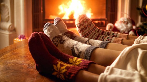 Imagen de primer plano de los pies de la familia en calcetines de lana que yacen junto a la chimenea
 - Foto, Imagen