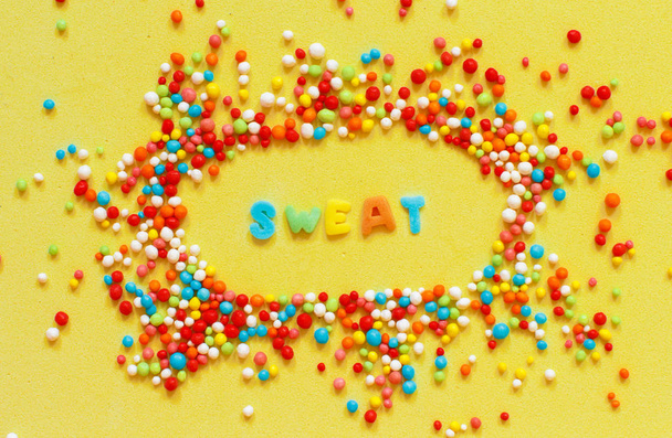 Colorful sugar sprinkles and a word Sweet on a bright yellow background - Photo, Image
