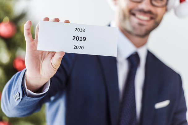 cropped image of businessman holding card with 2019 in office - Photo, Image