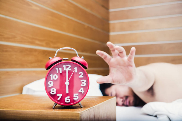 Hombre durmiendo en la cama con una alarma
 - Foto, imagen