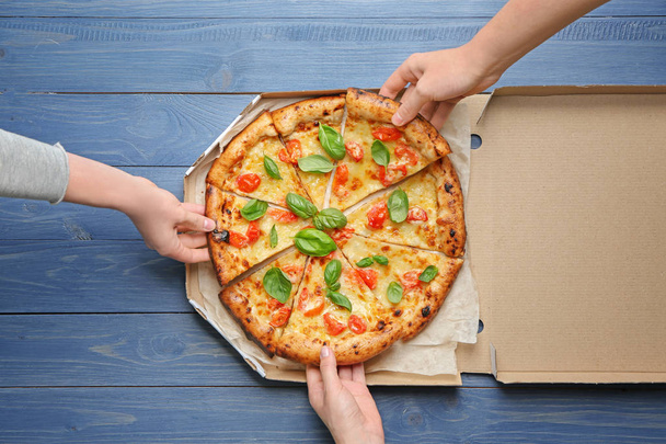 Młodzi ludzie plastrami pyszne pizza Margherita z pola - Zdjęcie, obraz