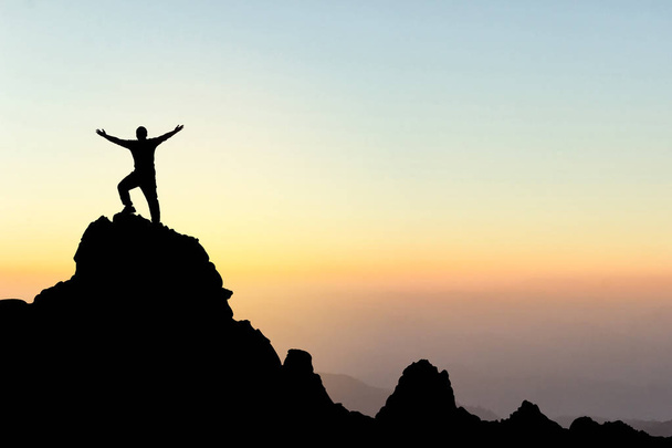 Σιλουέτα ενός ανθρώπου στην κορυφή ενός βουνού. Αθλητισμός και ενεργό ζωή έννοια - Φωτογραφία, εικόνα