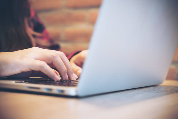 Immagine ravvicinata delle mani di una donna d'affari che lavora e digita sulla tastiera del computer portatile su un tavolo di legno - Foto, immagini