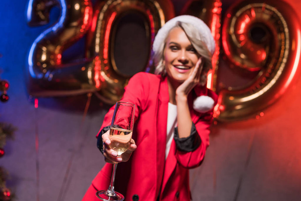 beautiful caucasian businesswoman in santa hat showing glass of champagne at new year corporate party - Φωτογραφία, εικόνα