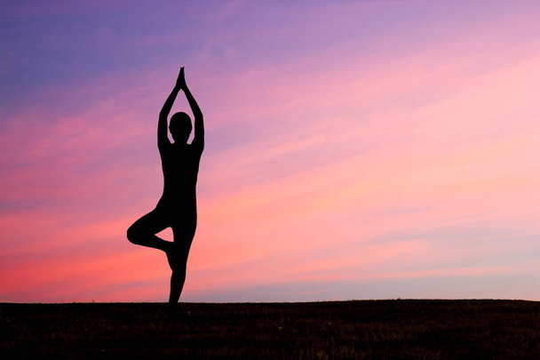 Silhouette of woman practicing yoga at sunset - Photo, Image
