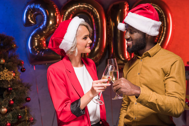 african american businessman and caucasian businesswoman clinking with glasses at new year corporate party - Фото, изображение