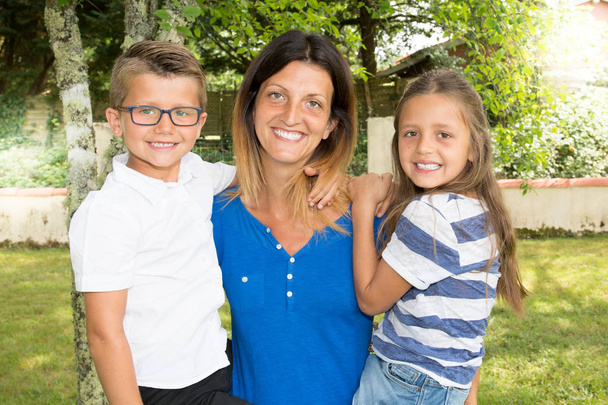 allegro genitore madre single famiglia moderna con due figli figlia e figlio in braccio in casa casa giardino
 - Foto, immagini