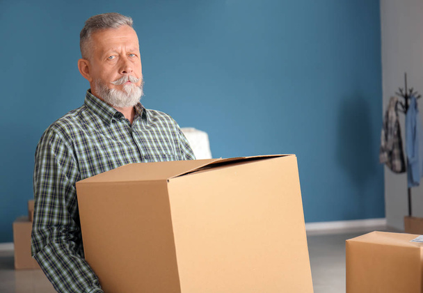 Зрелый мужчина с коробками для переездов в новом доме
 - Фото, изображение